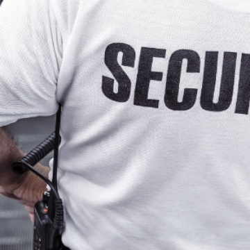 Person with security on back of shirt riding an escalator